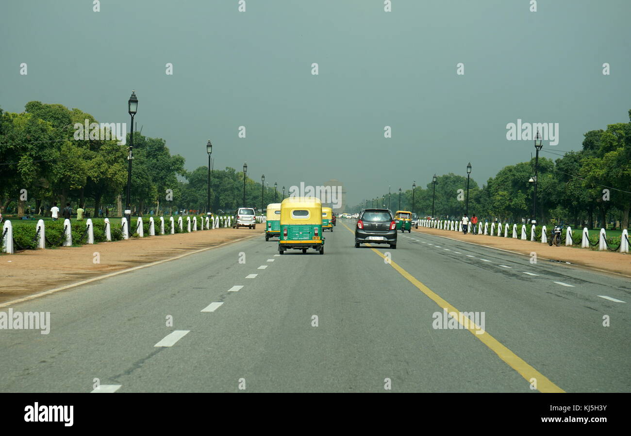Small yellow and green taxis drive towards the India Gete in Delhi, India Stock Photo
