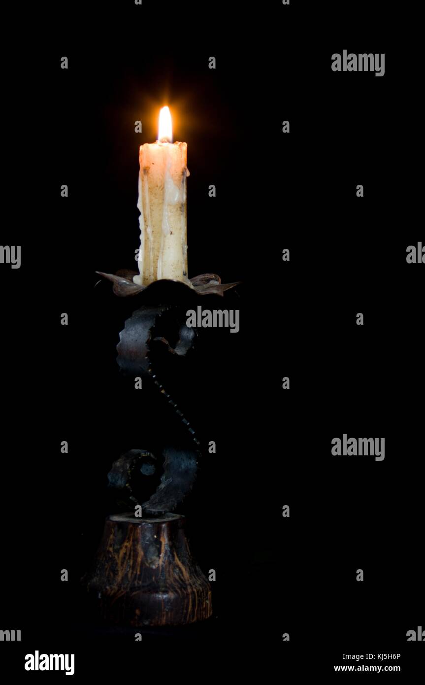 Lighted candle with the melted wax falling down in a chandelier