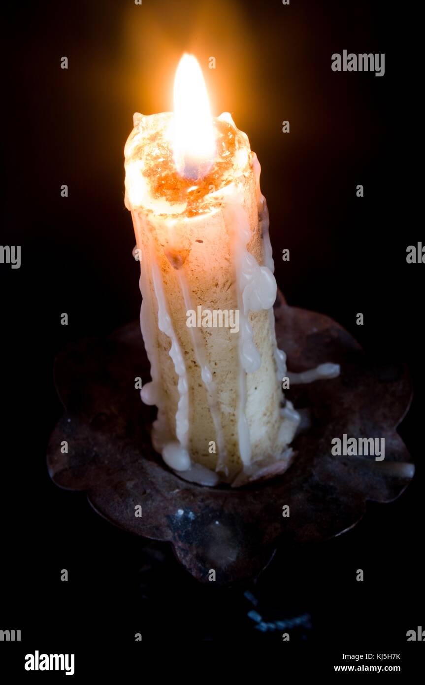 Lighted candle with the melted wax falling down in a chandelier