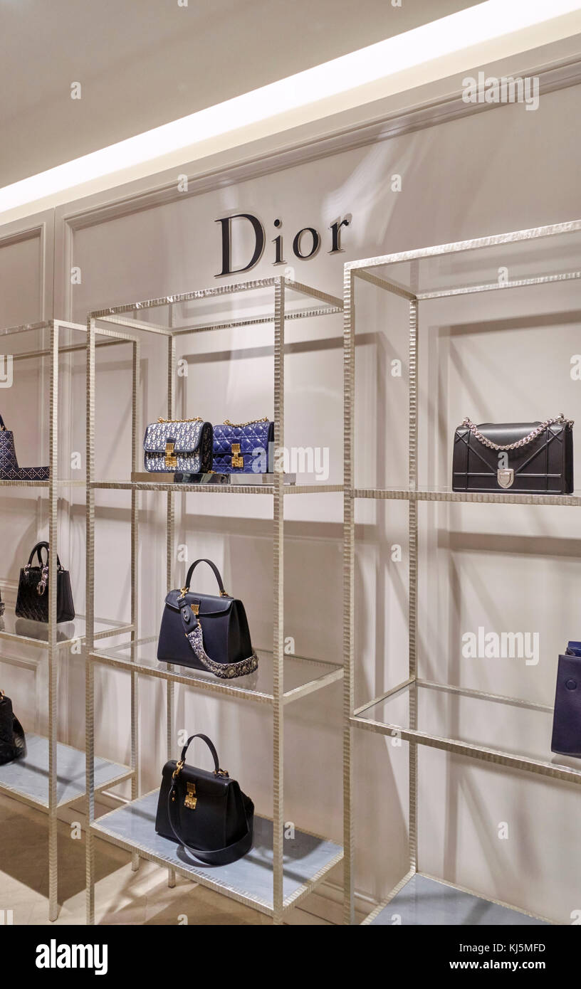 Elegant fashion store, bags and leather accessories on the shelves of Christian Dior shop Stock Photo
