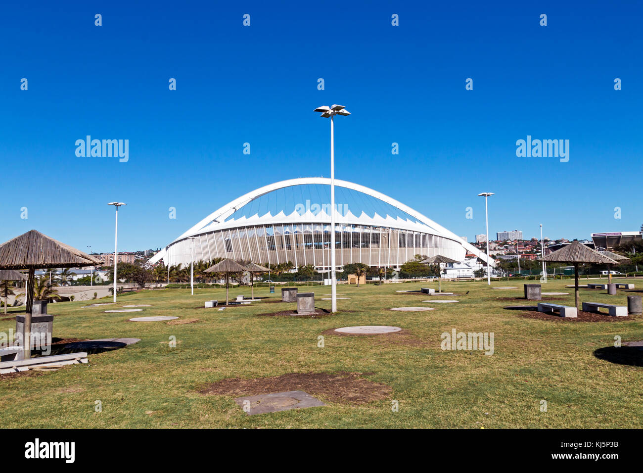 Grass lawn recreational area against Moses Mabhida stadium and blue sky