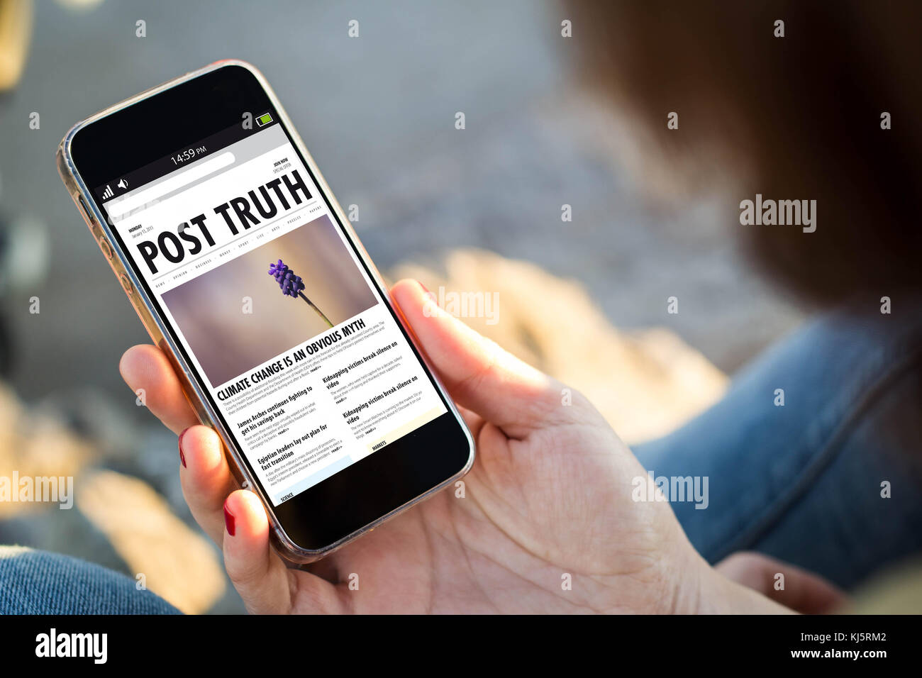 close-up view of young woman checking post truth news her mobile phone. All screen graphics are made up. Stock Photo