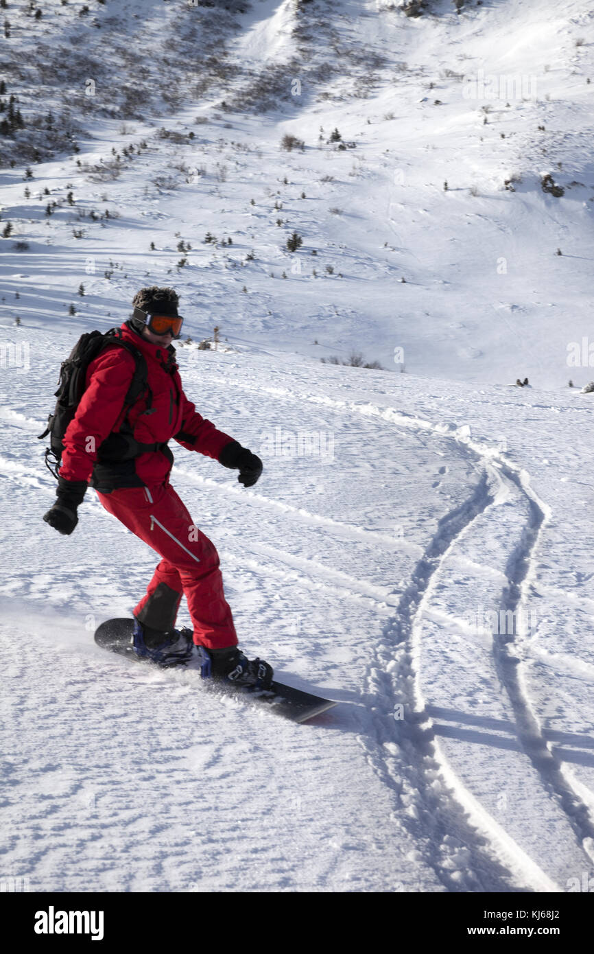 Snowboarder downhill on snow off piste slope in sun winter morning