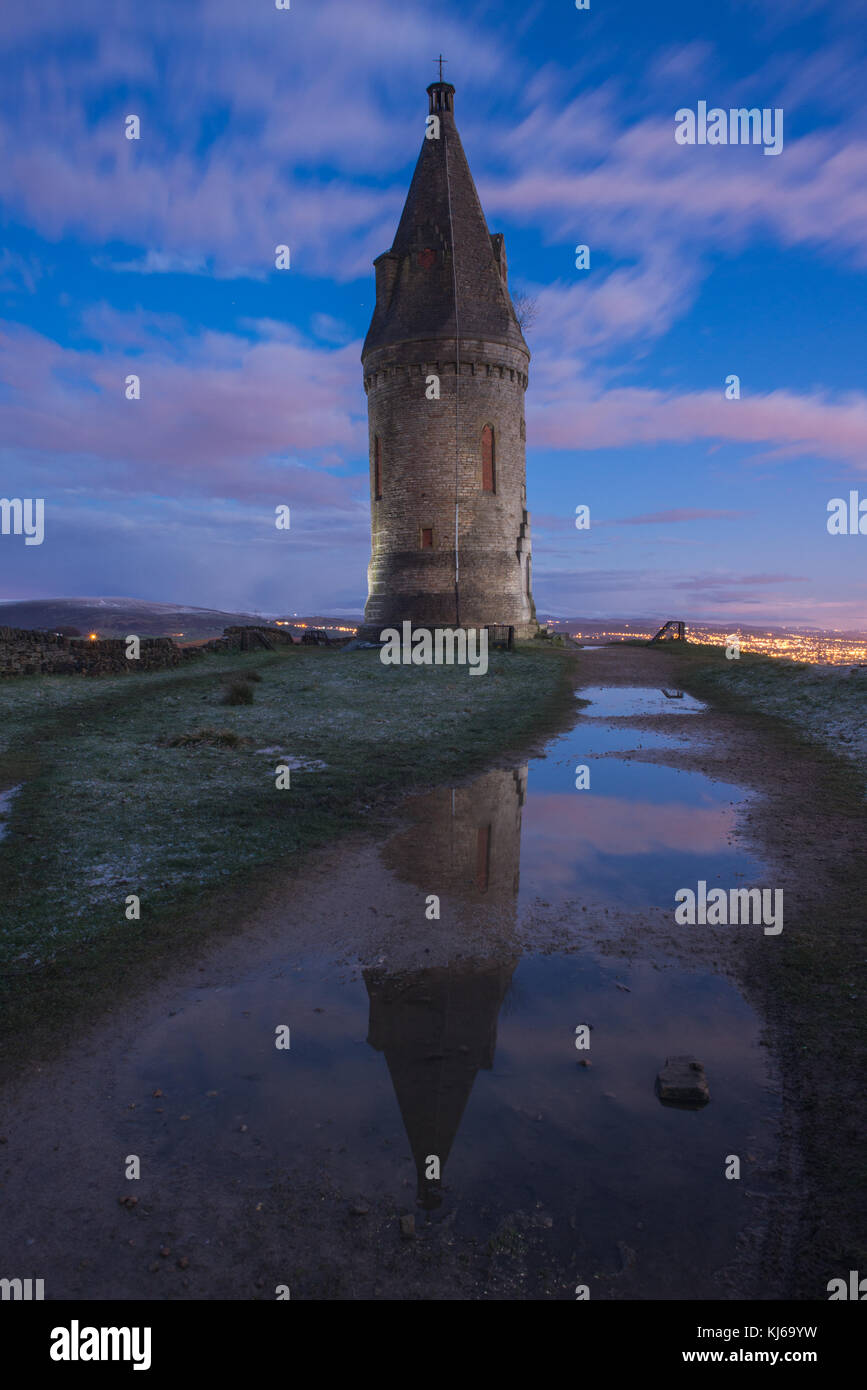 Hartshead Pike, Saddleworth is reflected in a puddle at sunset in April ...