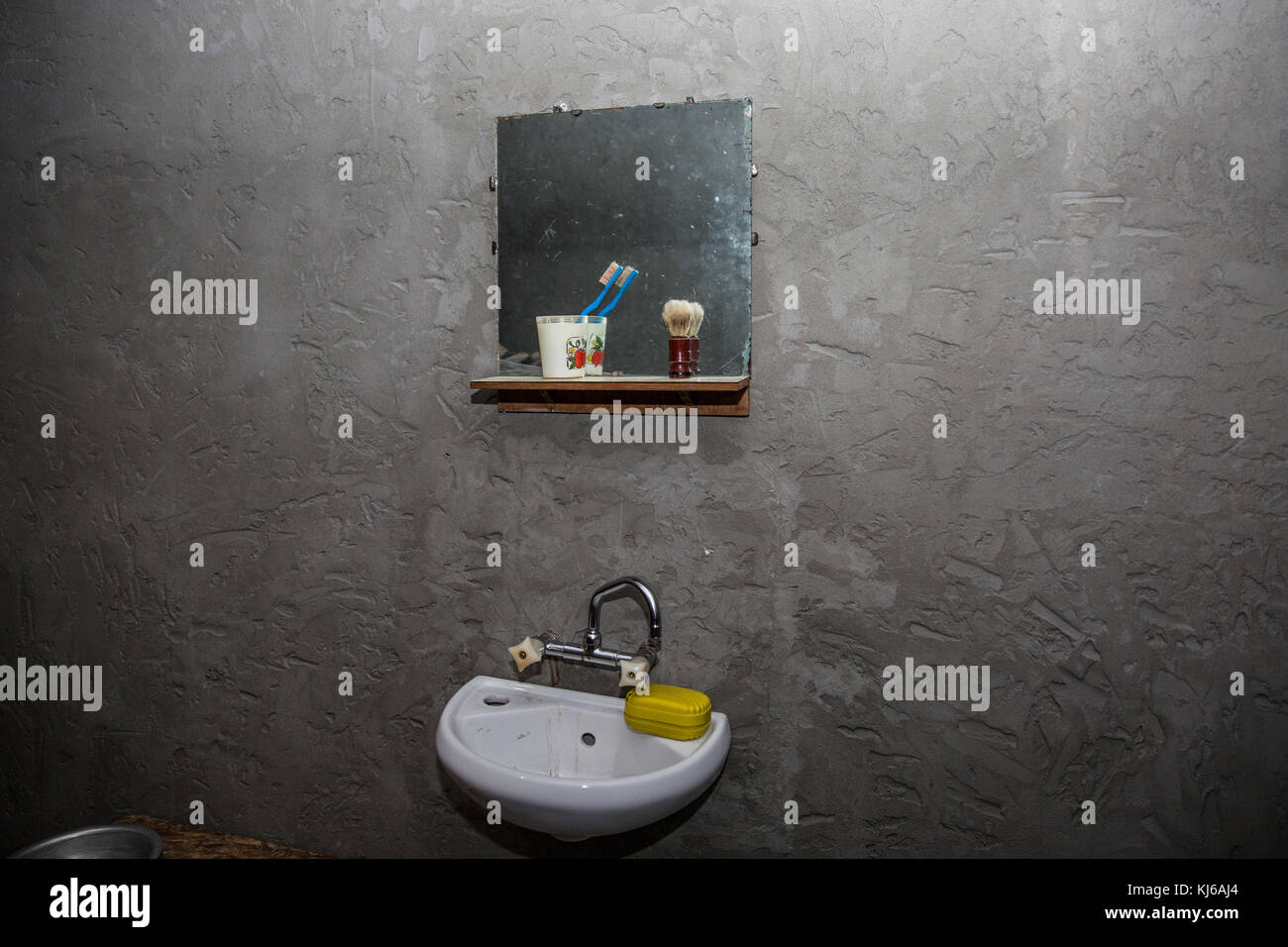 Dirty washbasin in an old poor house. Mirror, tooth count. A dark, sombre abstract scene about poverty and housing problems. Stock Photo
