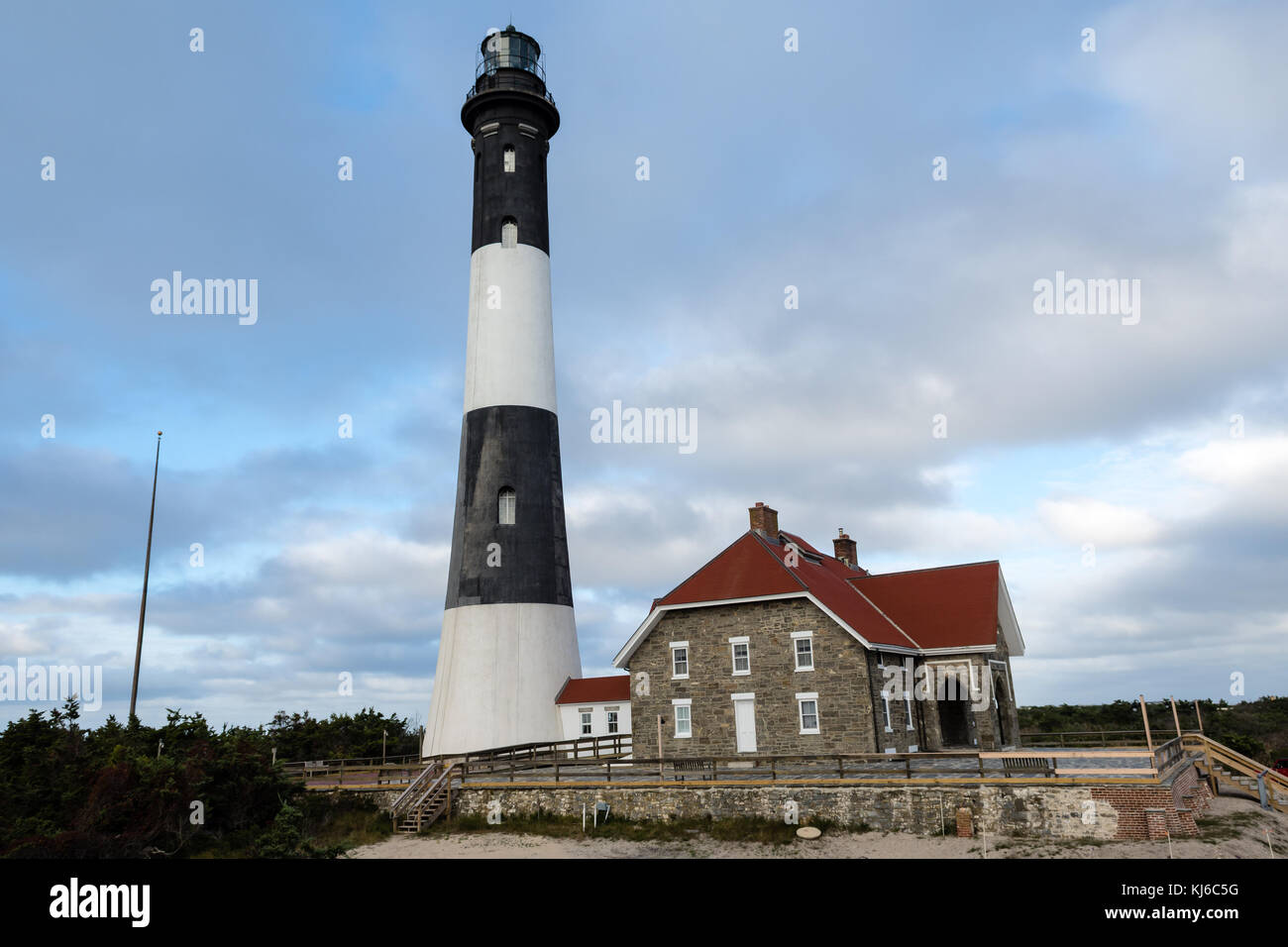 Over the lighthouse and the caretaker's house floating white clouds in the blue sky Stock Photo
