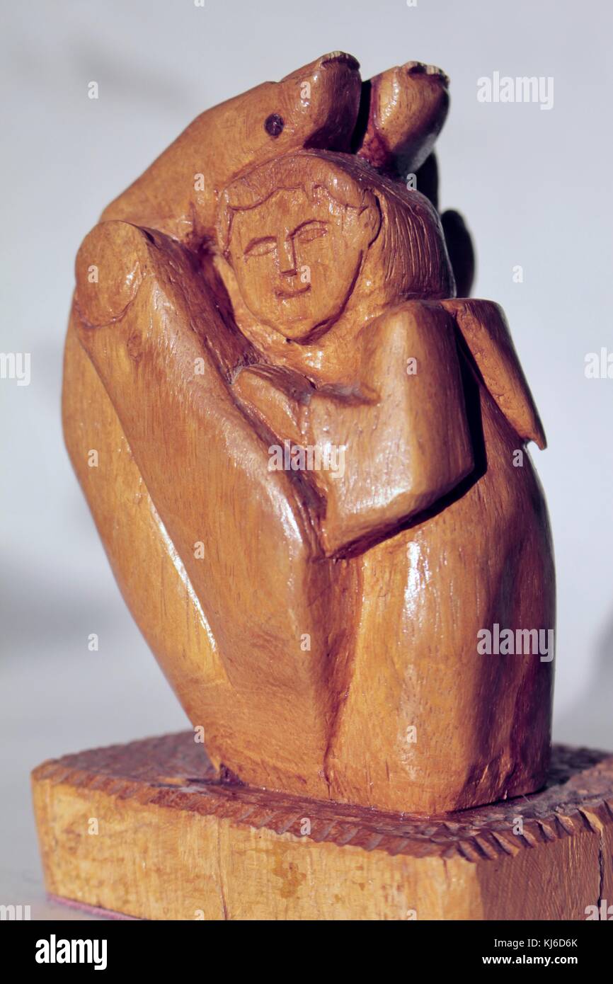Small wooden carving, sculpture, of God's hand holding and protecting a monk Stock Photo