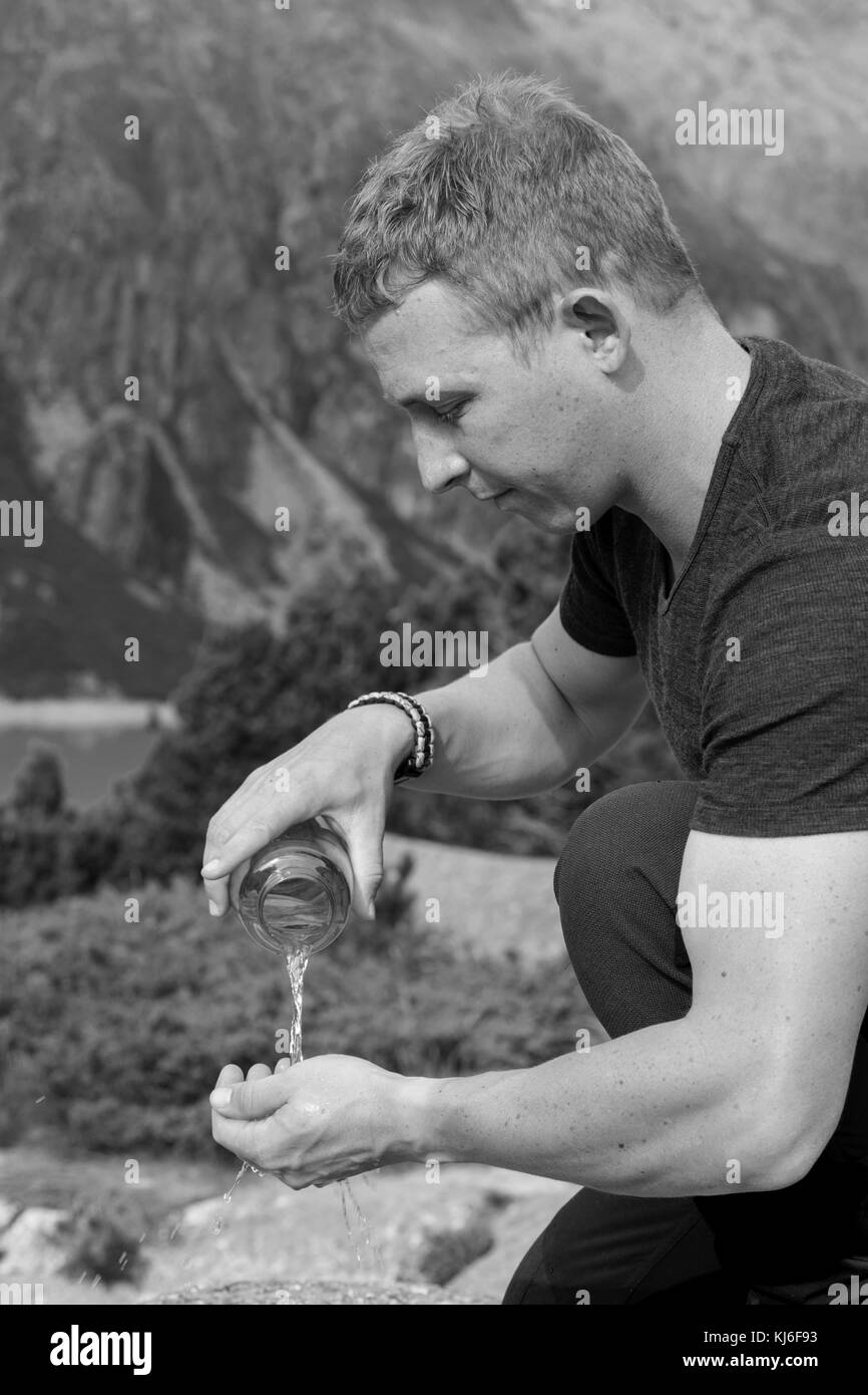 Hiker pours water from a water bottle on his hands Stock Photo