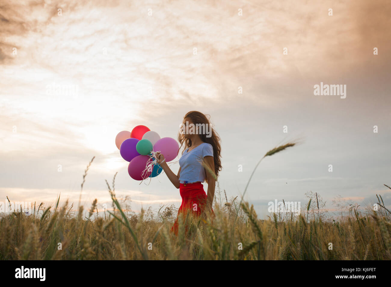 Girl with balloons in wheat field Stock Photo - Alamy