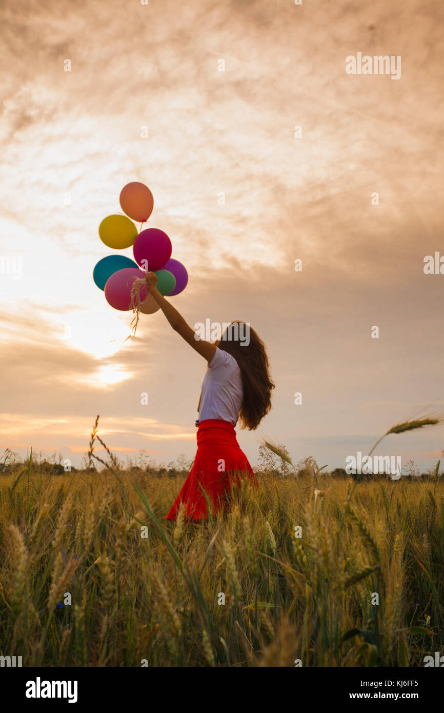 Girl with balloons in wheat field Stock Photo - Alamy