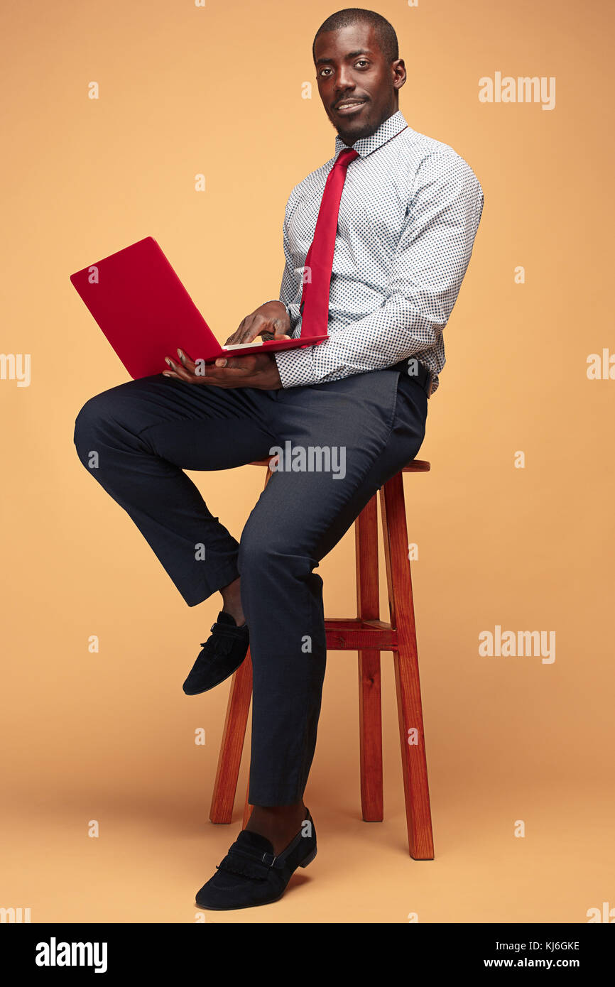 Handsome Afro American man sitting and using a laptop Stock Photo - Alamy