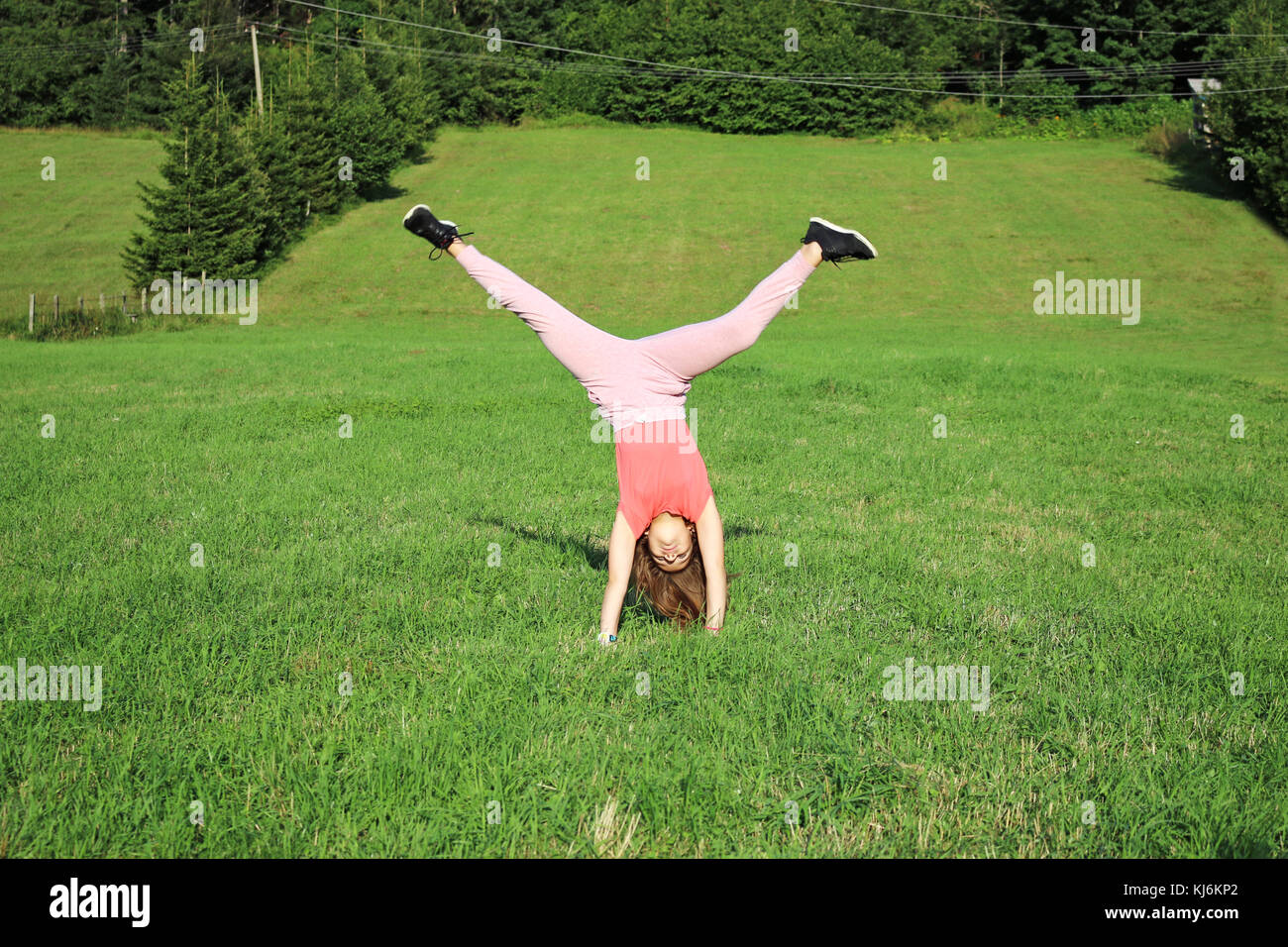 little girl doing catwheel on green field Stock Photo