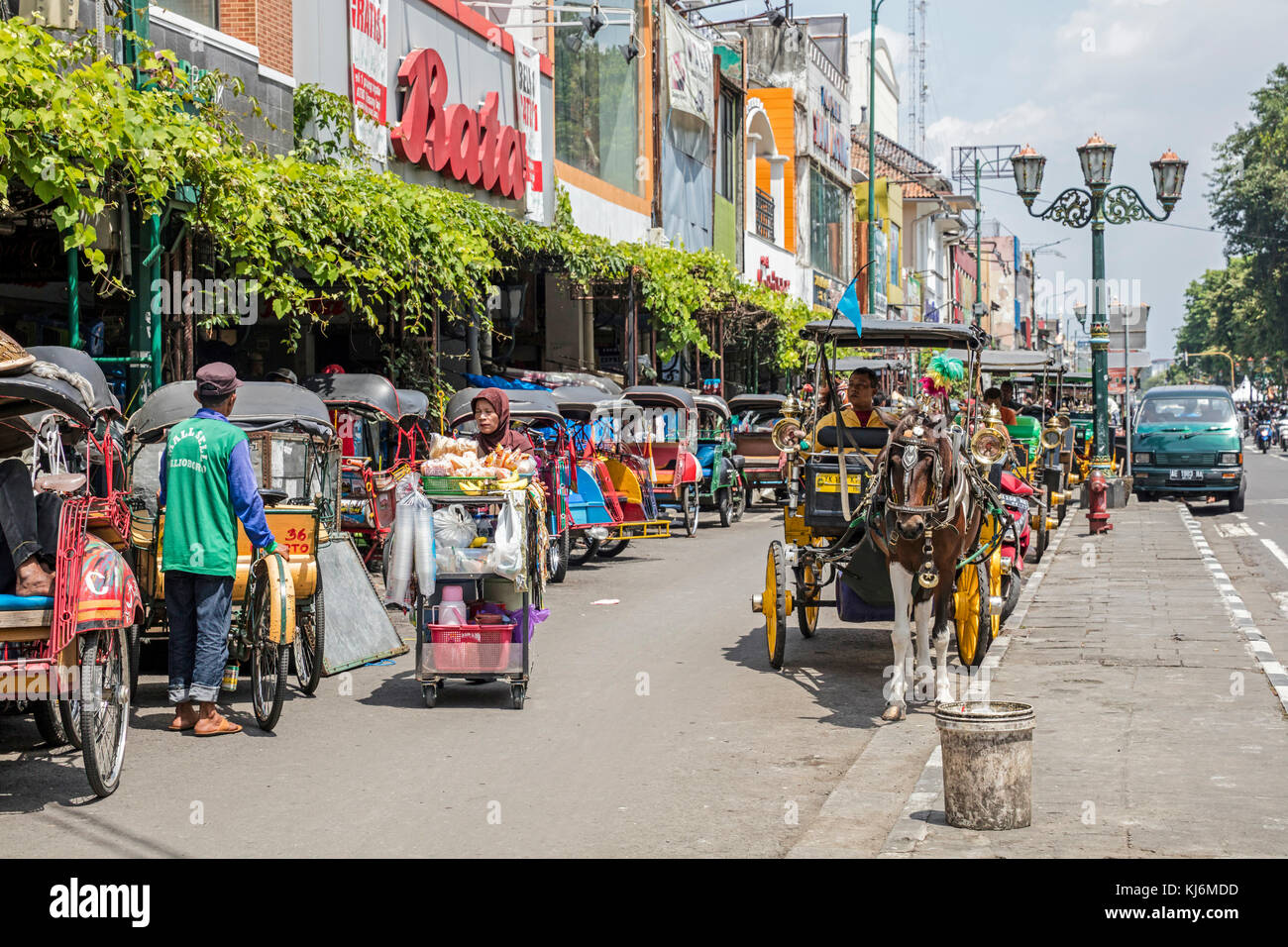 Cycle rickshaws / becak and horse-drawn carriages for public transport in Jalan Malioboro, major shopping street in Yogyakarta, Java, Indonesia Stock Photo
