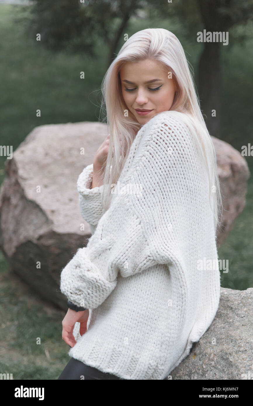 Young blonde female wearing knitted white sweater. Women fashion concept Stock Photo