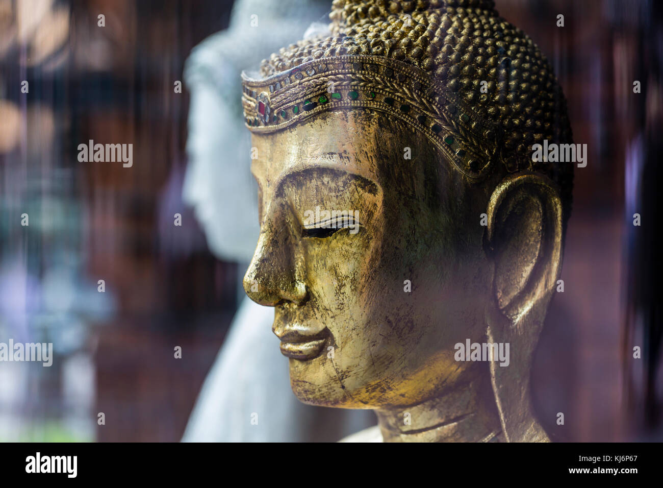 The head of a gold colour statue of buddha behind a restaurant window, Scotland, UK Stock Photo