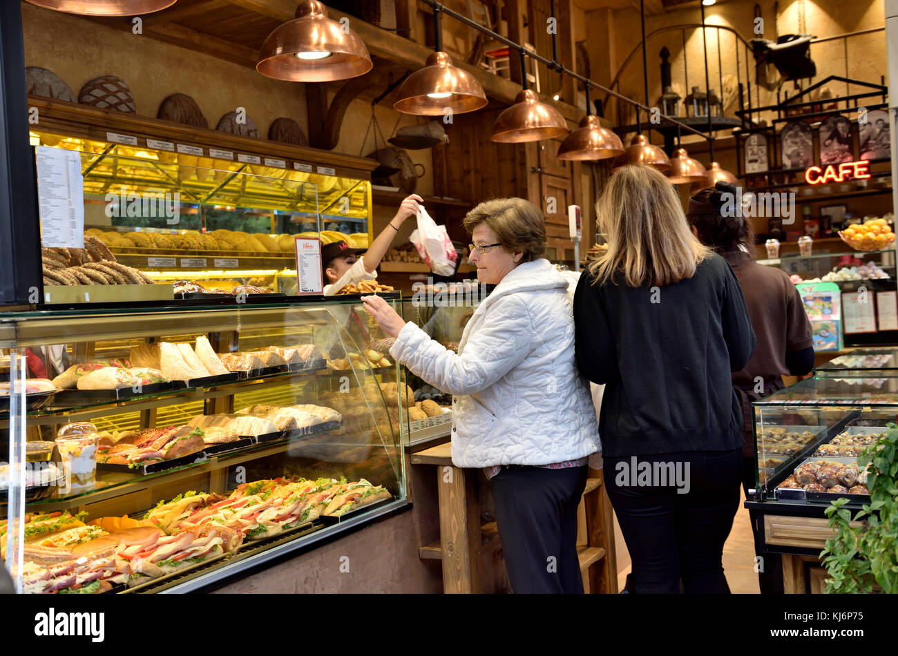 Woman inside of Greek bakery shop cafe selecting sandwich from display, Athens, Greece Stock Photo