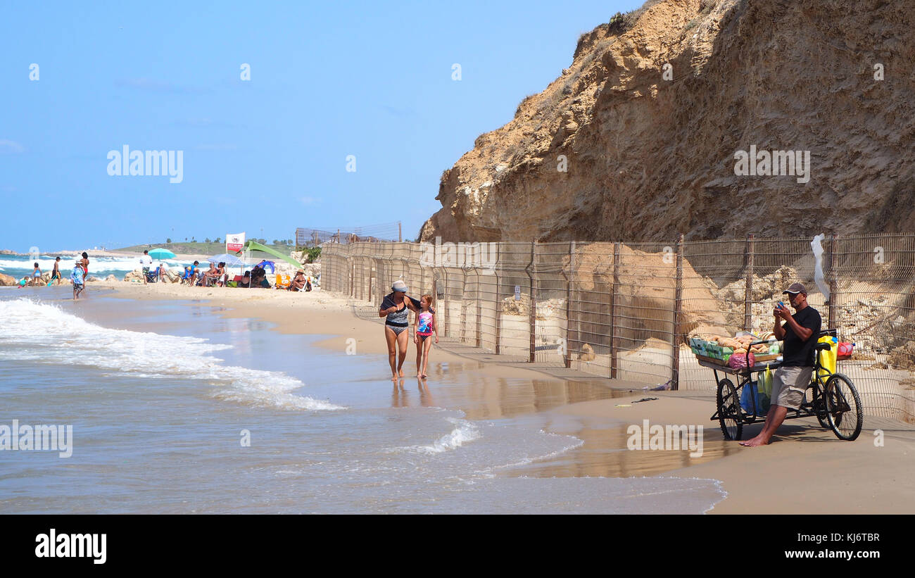 mother and child walking on the beach and peddler with tricycle Stock Photo