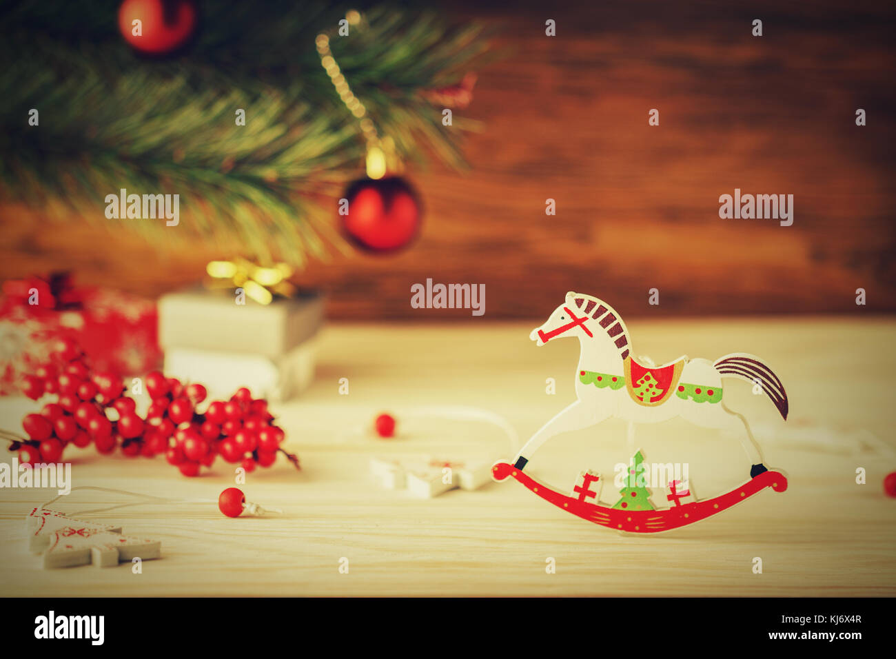 Christmas card in retro style Wooden horse on blurred background Fir tree and balls
