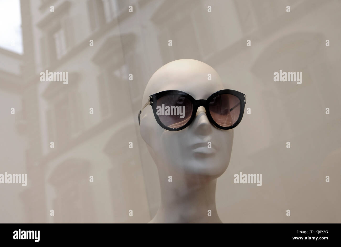 bald mannequin model wearing sunglasses in fashion store window
