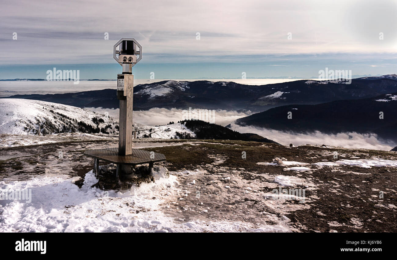 Binoculars on the top of a snowy mountain with a dramatic view in the background. Stock Photo