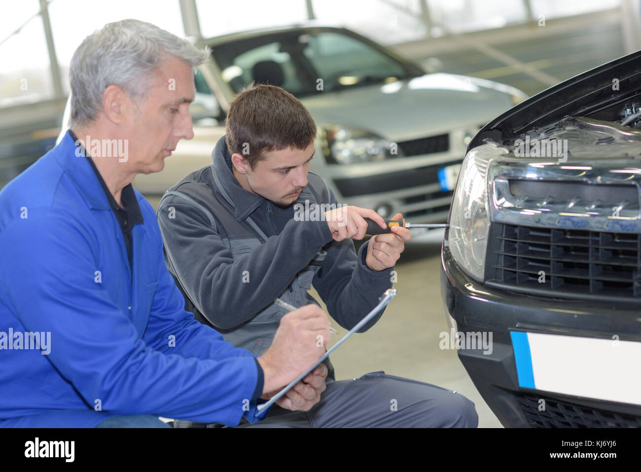 student and teacher mechanics changing car headlight in a workshop ...