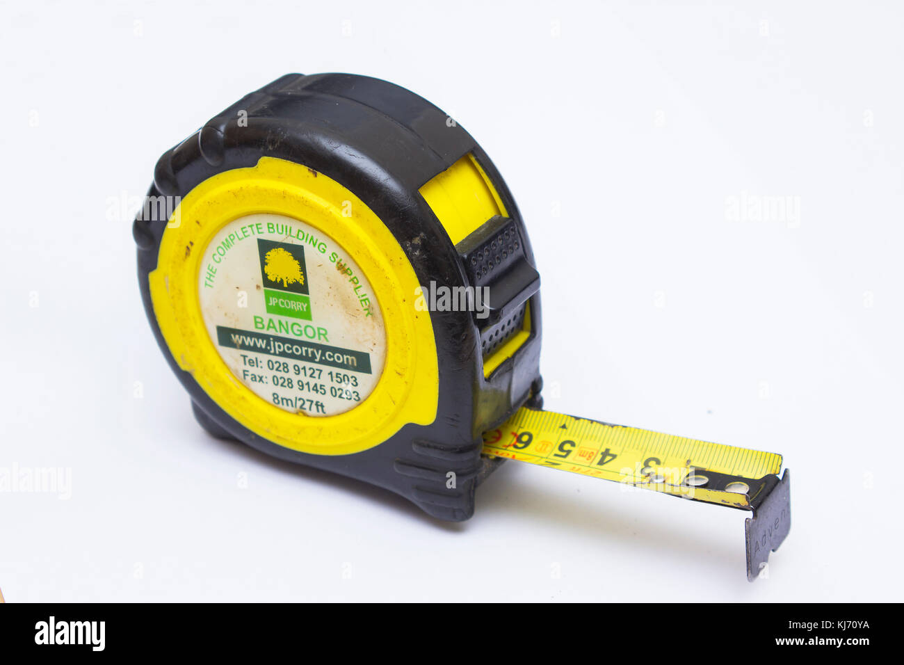 An old and well used retractable tape measure with metric and imperial measure bearing the suppliers name and address in Bangor county Down in Norther Stock Photo