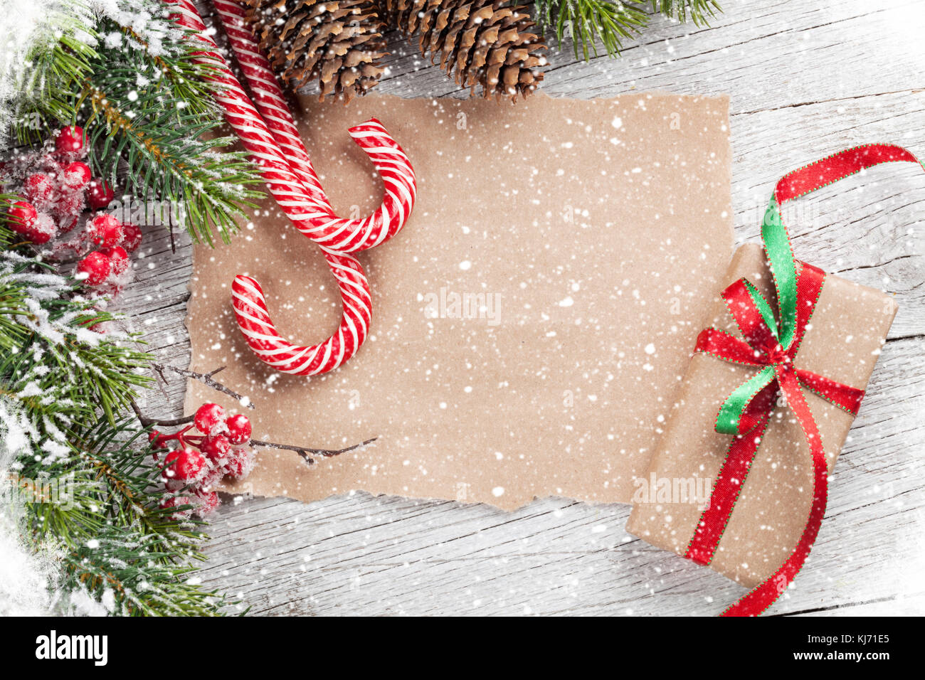 Christmas gift box, candy cane and snow fir tree on wooden table. Top ...