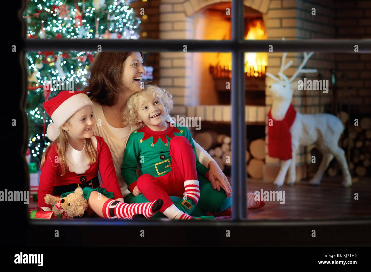 Family With Kids At Christmas Tree And Fireplace Mother And