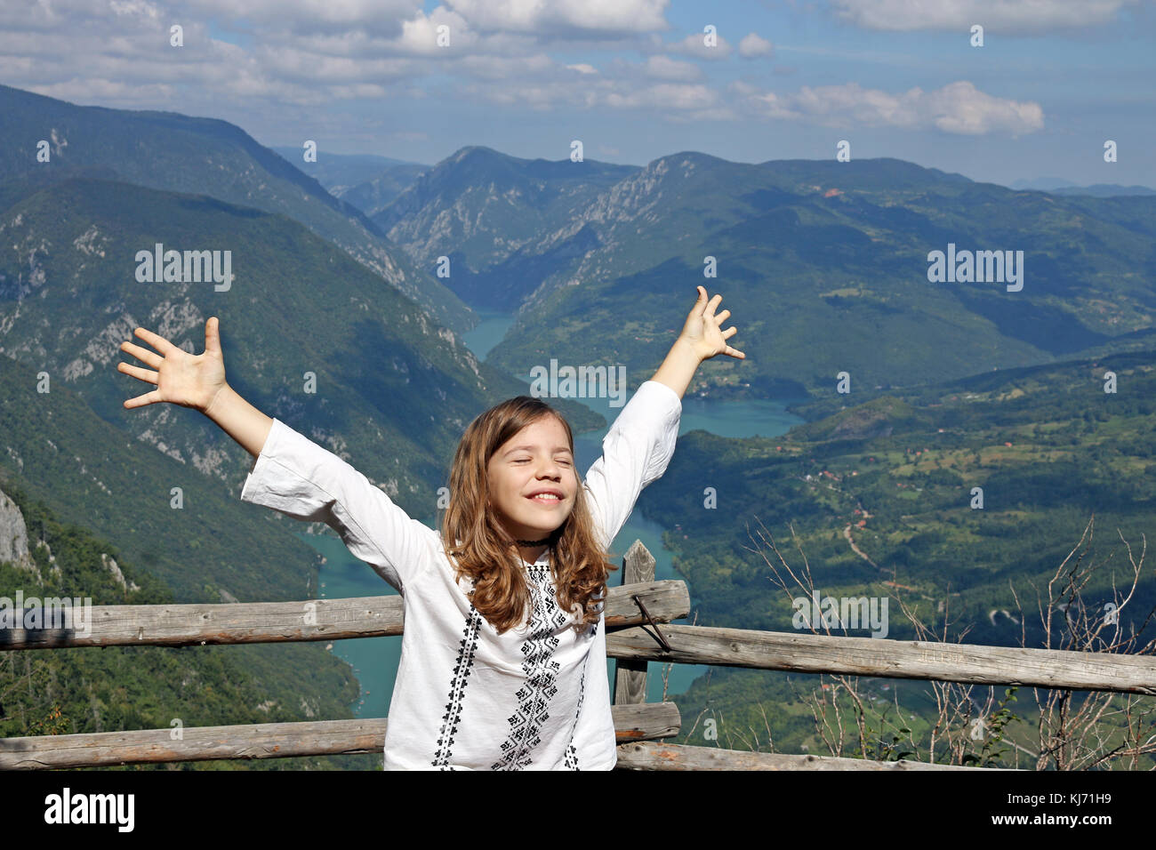 happy little girl with hands up on mountain Stock Photo