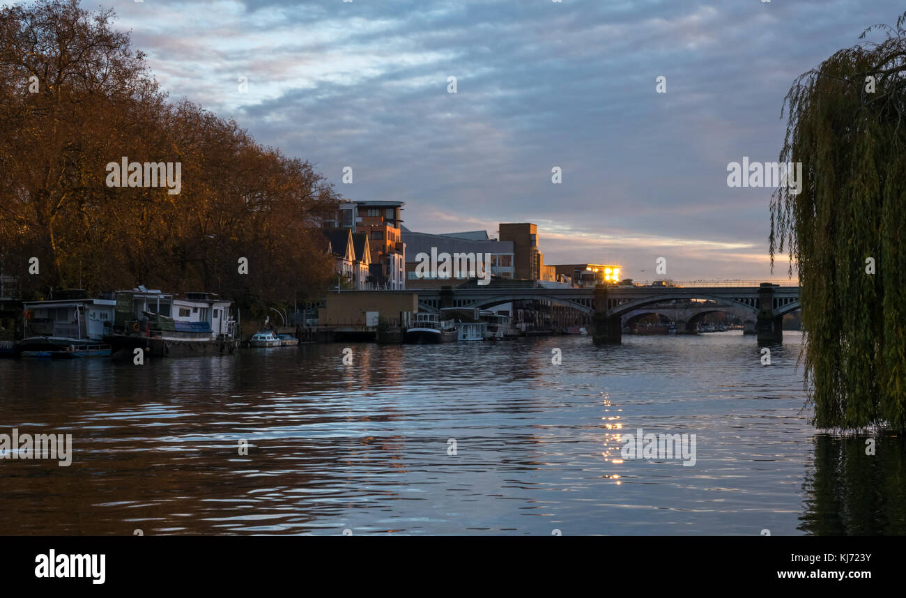 Autumn sunset, Thames River, Hampton Wick, looking West up river towards Kingston bridge, London, England, UK, with barges and water reflections Stock Photo
