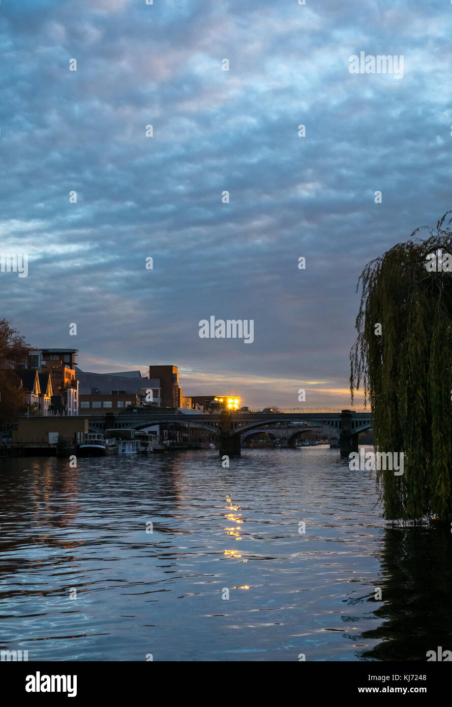 Autumn sunset colours on River Thames, Hampton Wick looking West up river to Kingston Bridge, London, England, UK with reflected sun glare Stock Photo