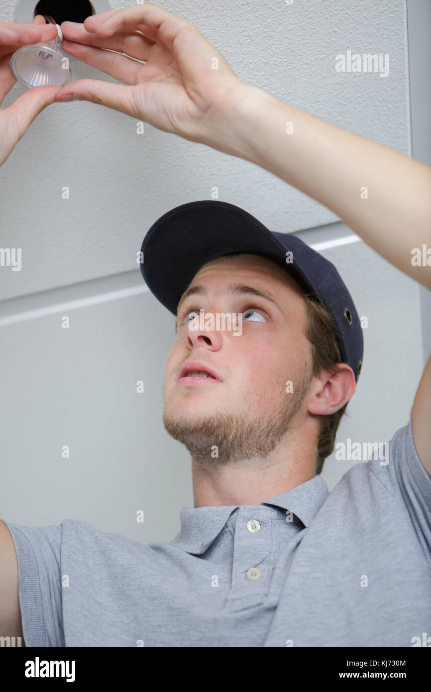 young male electrician fixing light on ceiling Stock Photo - Alamy