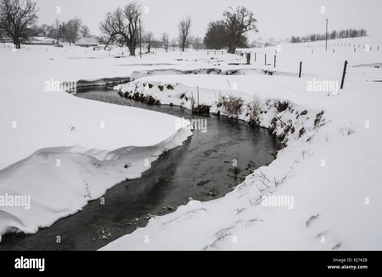 A stream meandering through Amish farmland, Lancaster County, rural Pennsylvania, USA, US, Amish country snow storm snowy field winter Landscape Stock Photo