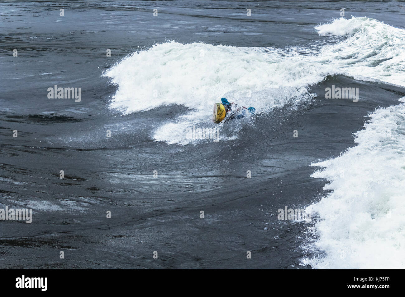 A kayaker begins an intentional roll in huge waves at Sechelt Rapids ('Skookumchuck'), one of the world's fastest tidal passes (British Columbia). Stock Photo