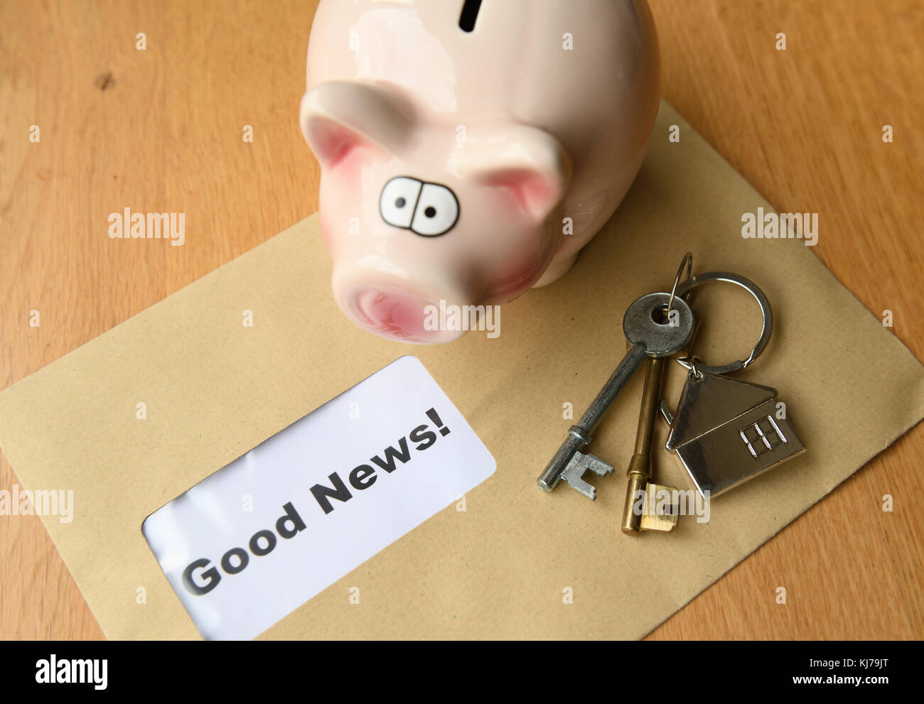 Concept of good news with piggy bank house keys and an envelope with good news inside Stock Photo