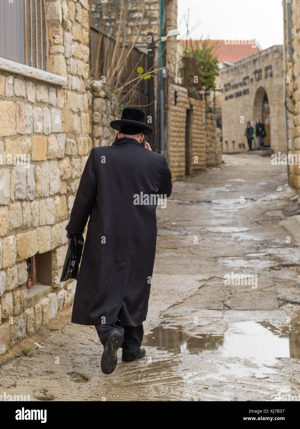 Rear view of man walking in wet street, Safed, Northern District, Israel Stock Photo