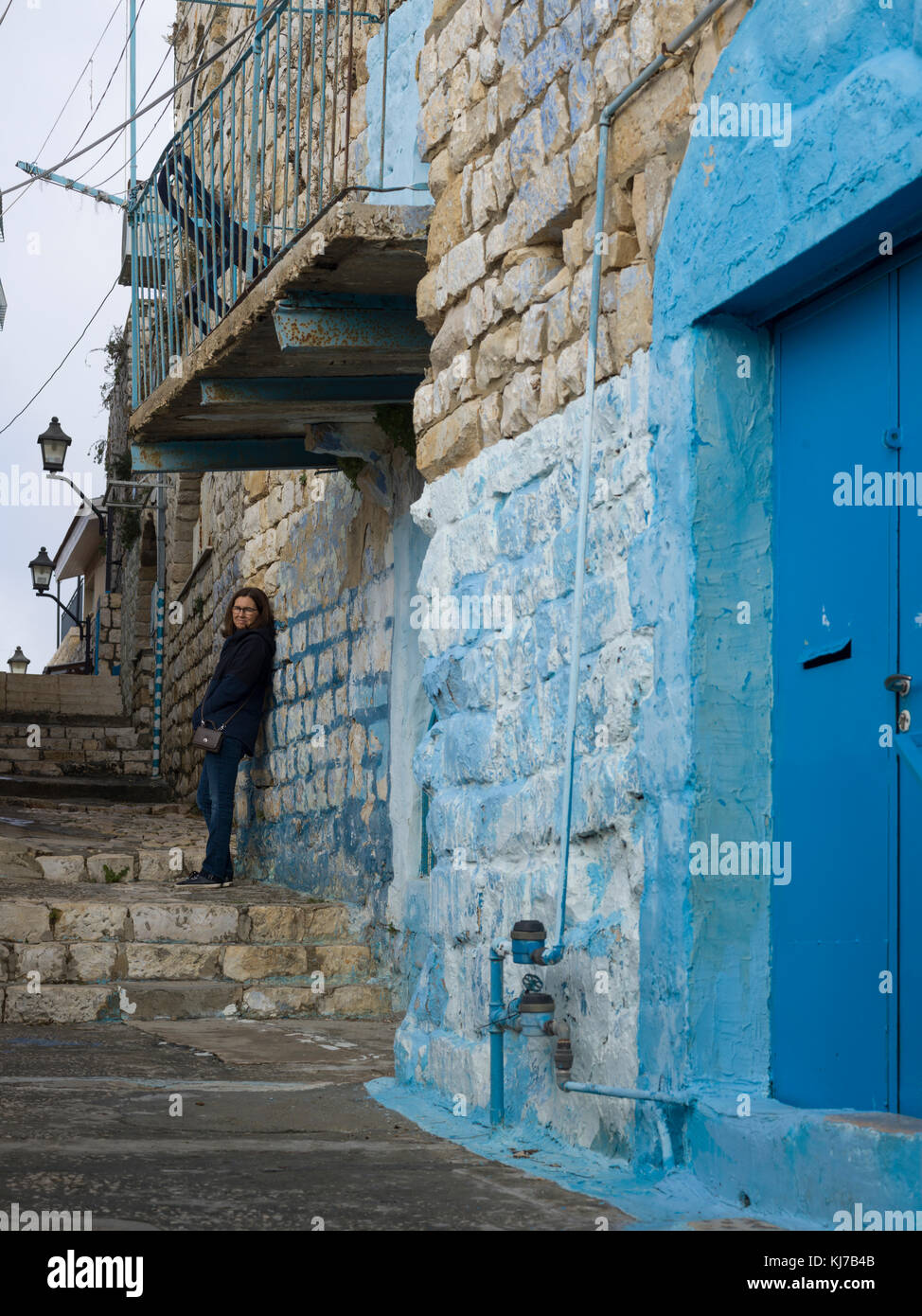 Woman leaning on stone wall in street, Safed, Northern District, Israel Stock Photo