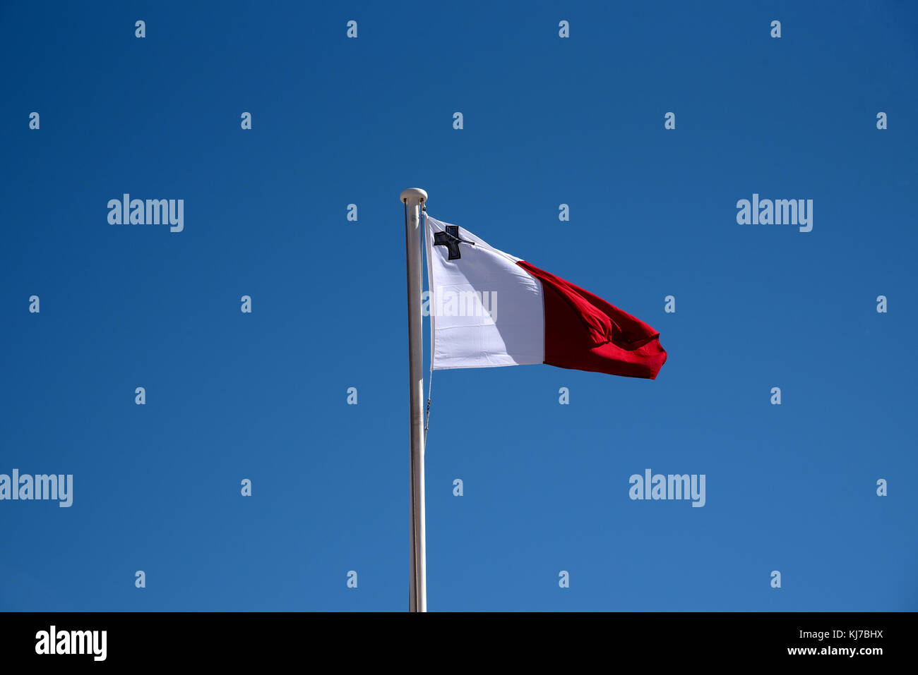 Maltese Flag against a blue sky fluttering in the wind Stock Photo