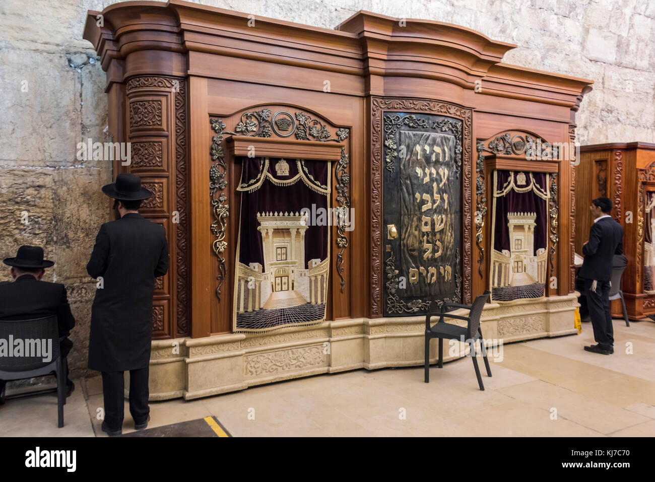 Jewish men praying near wooden cabinet with Torah scrolls in Cave