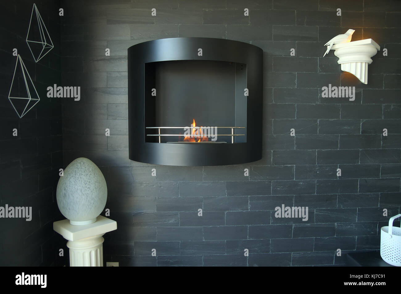 Wall-mount bio-ethanol fireplace on a black brickwall with lamps and decoration, in a french home Stock Photo