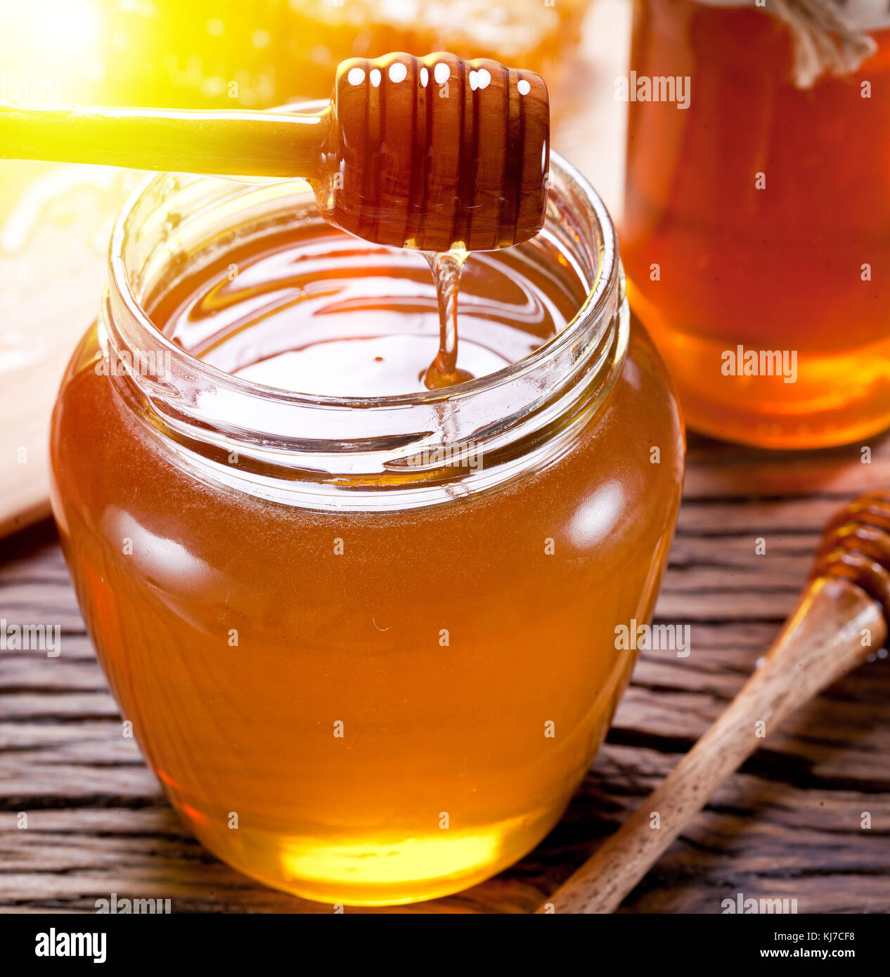 Honey dripping from a dipper into the jar full of fresh honey. Stock Photo