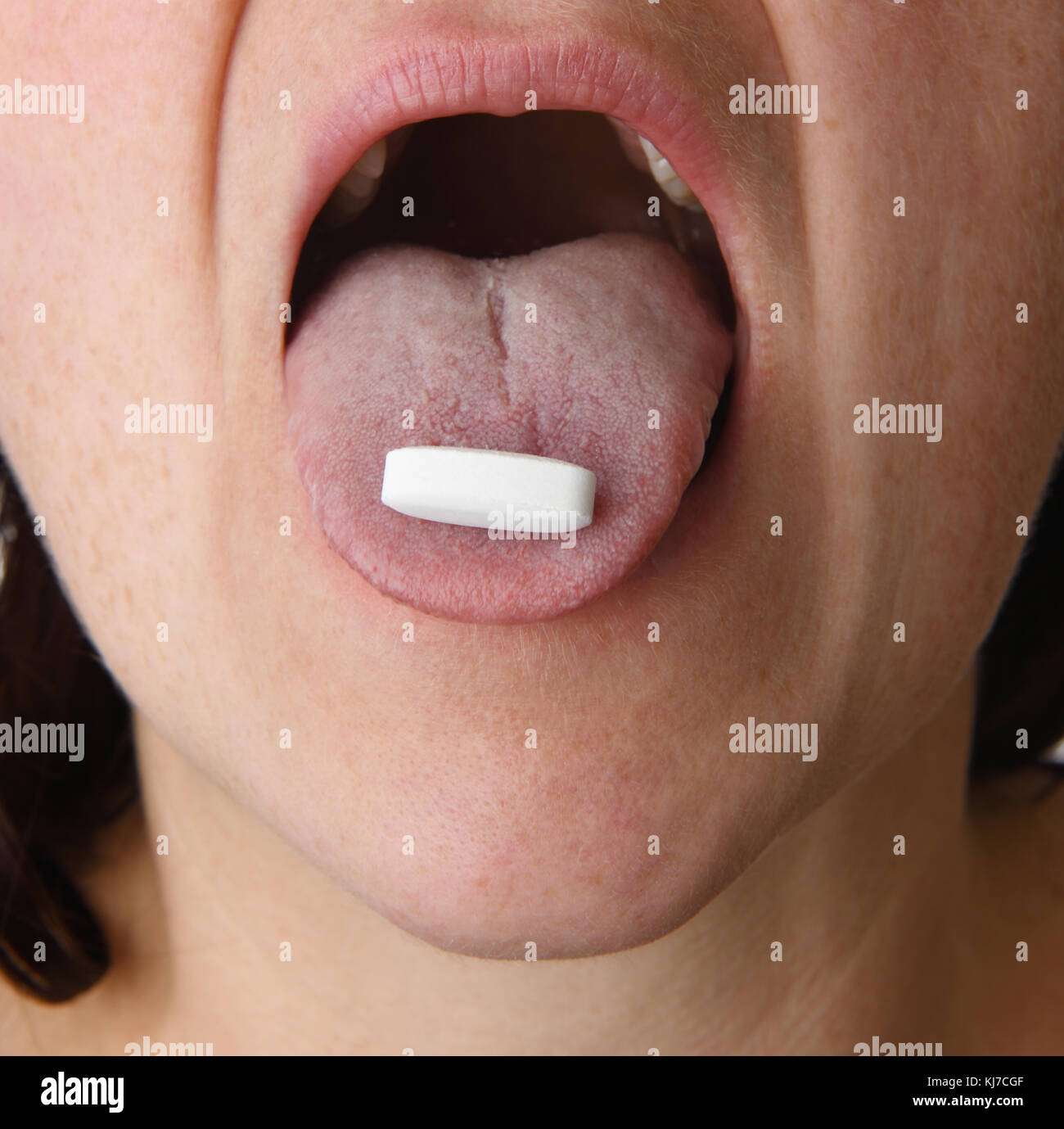 woman mouth open and tongue out with pill Stock Photo