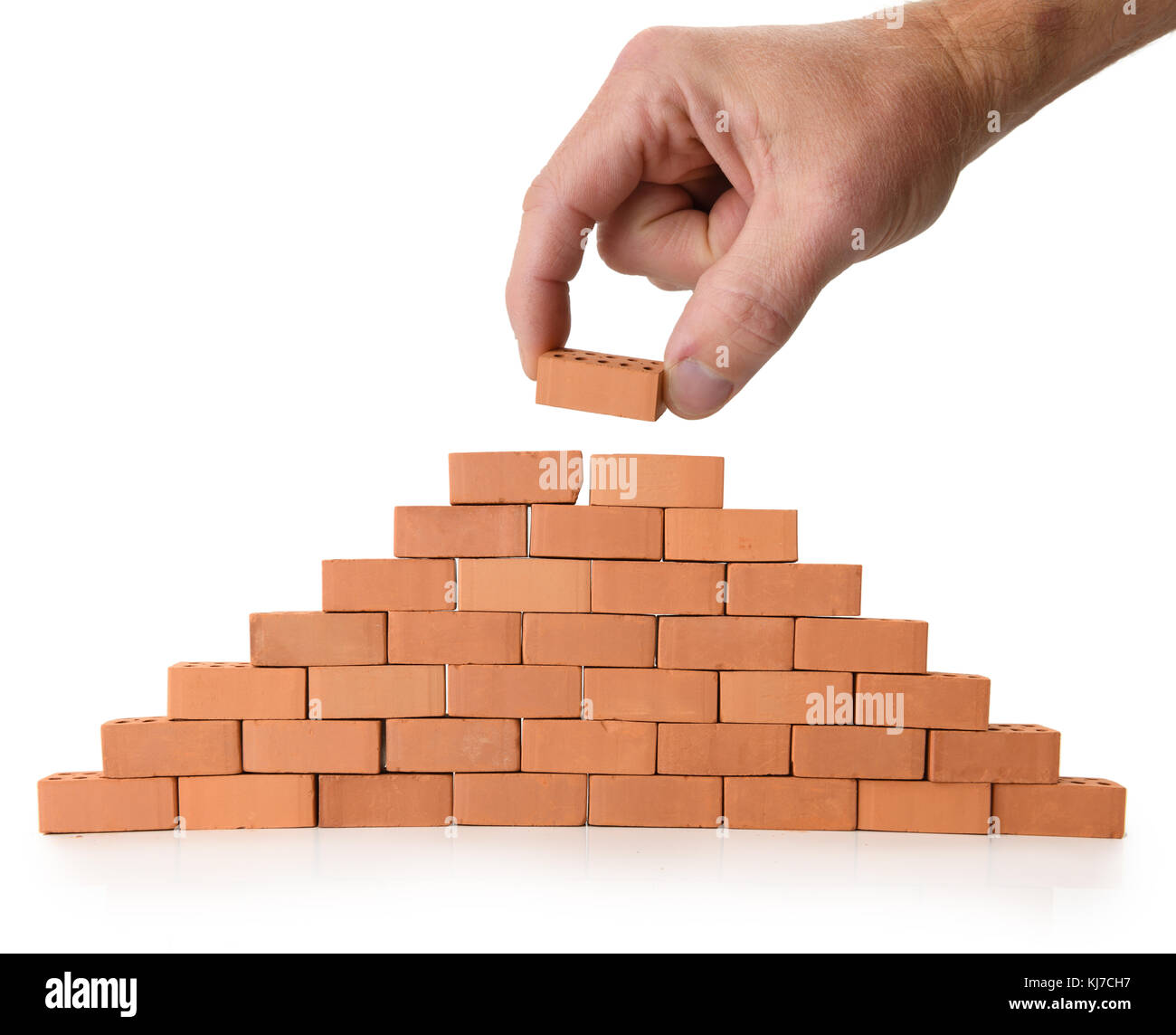 Concept of building and construction, a hand placing a brick on a wall, isolated on a white background Stock Photo