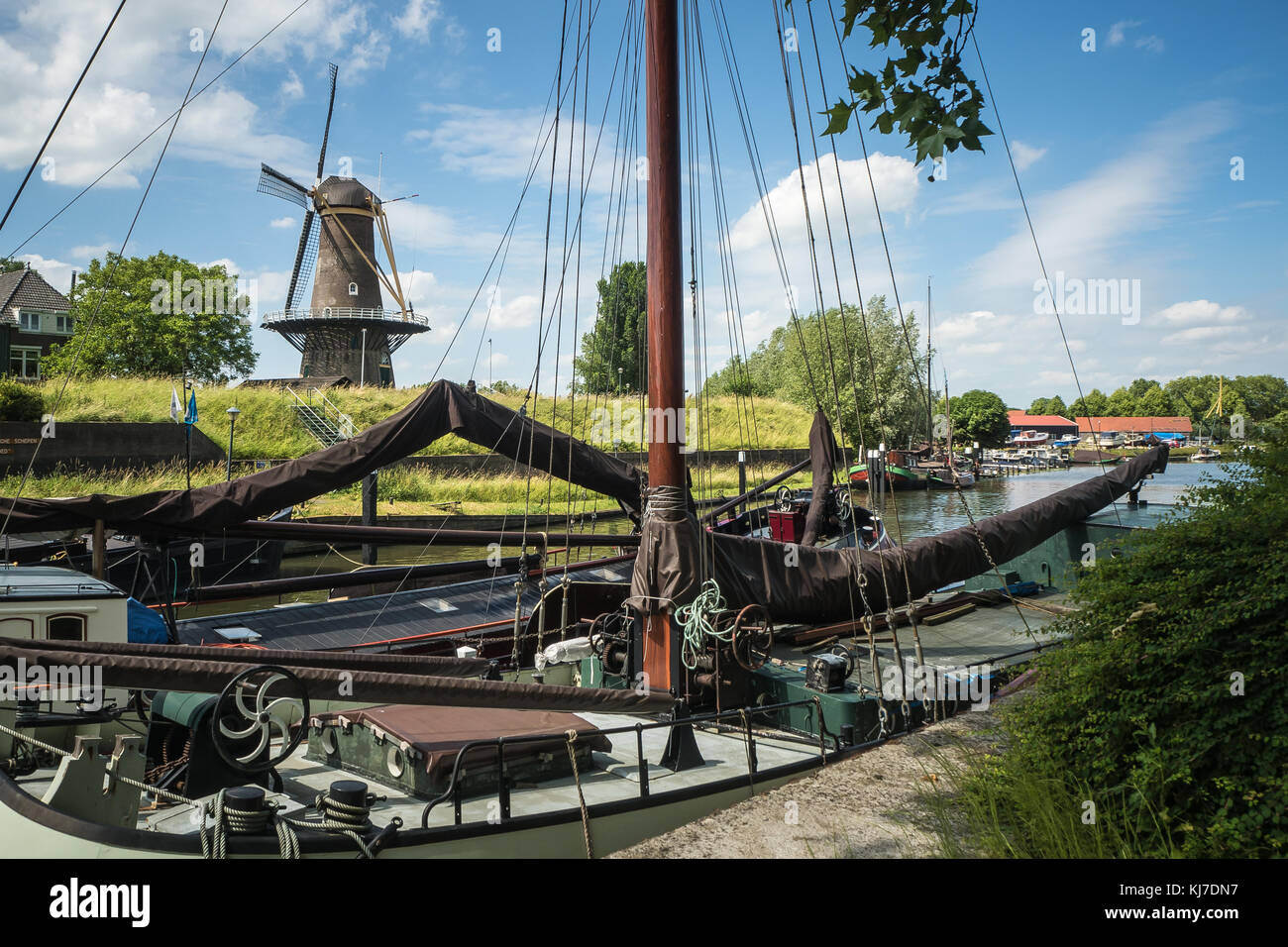 Typical Dutch Windmill Nooit Volmaakt in Gorinchem, Holland, with with historic sailing ships in the foreground Stock Photo