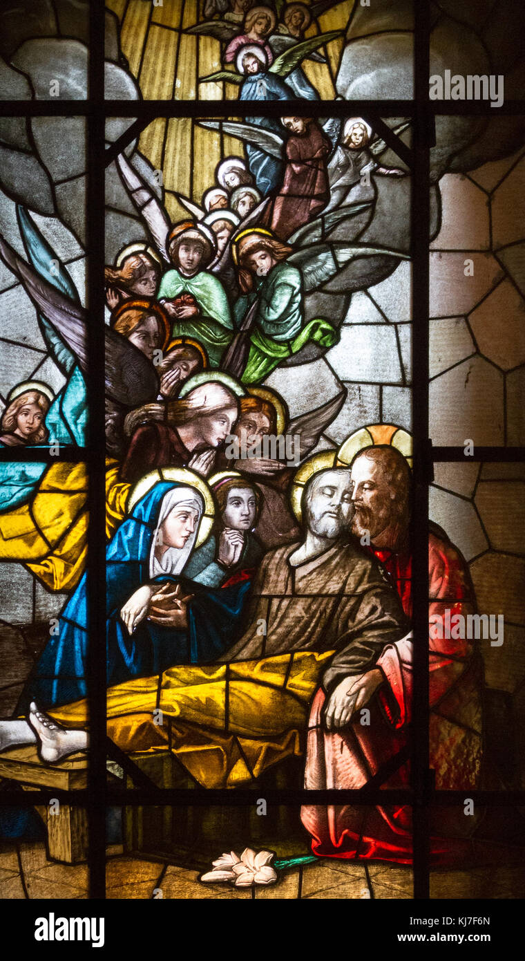 Stained glass depicting the death of Saint Joseph. Jesus Christ, Virgin Mary and myriads of angels attend. San Vittore Martire Church (Church of Saint Stock Photo