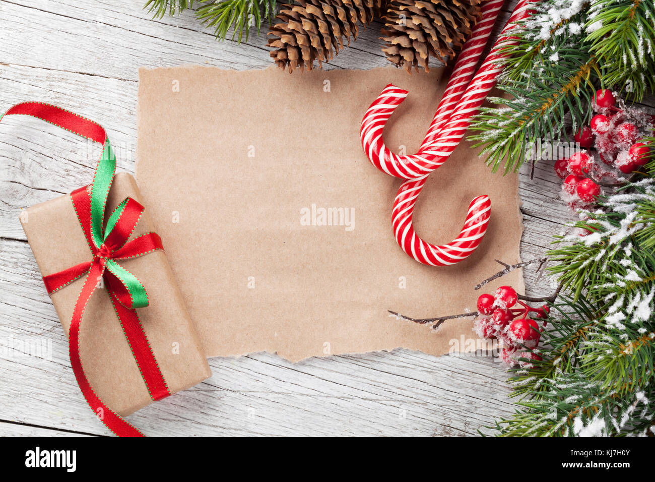 Christmas gift box, candy cane and snow fir tree on wooden table. Top ...