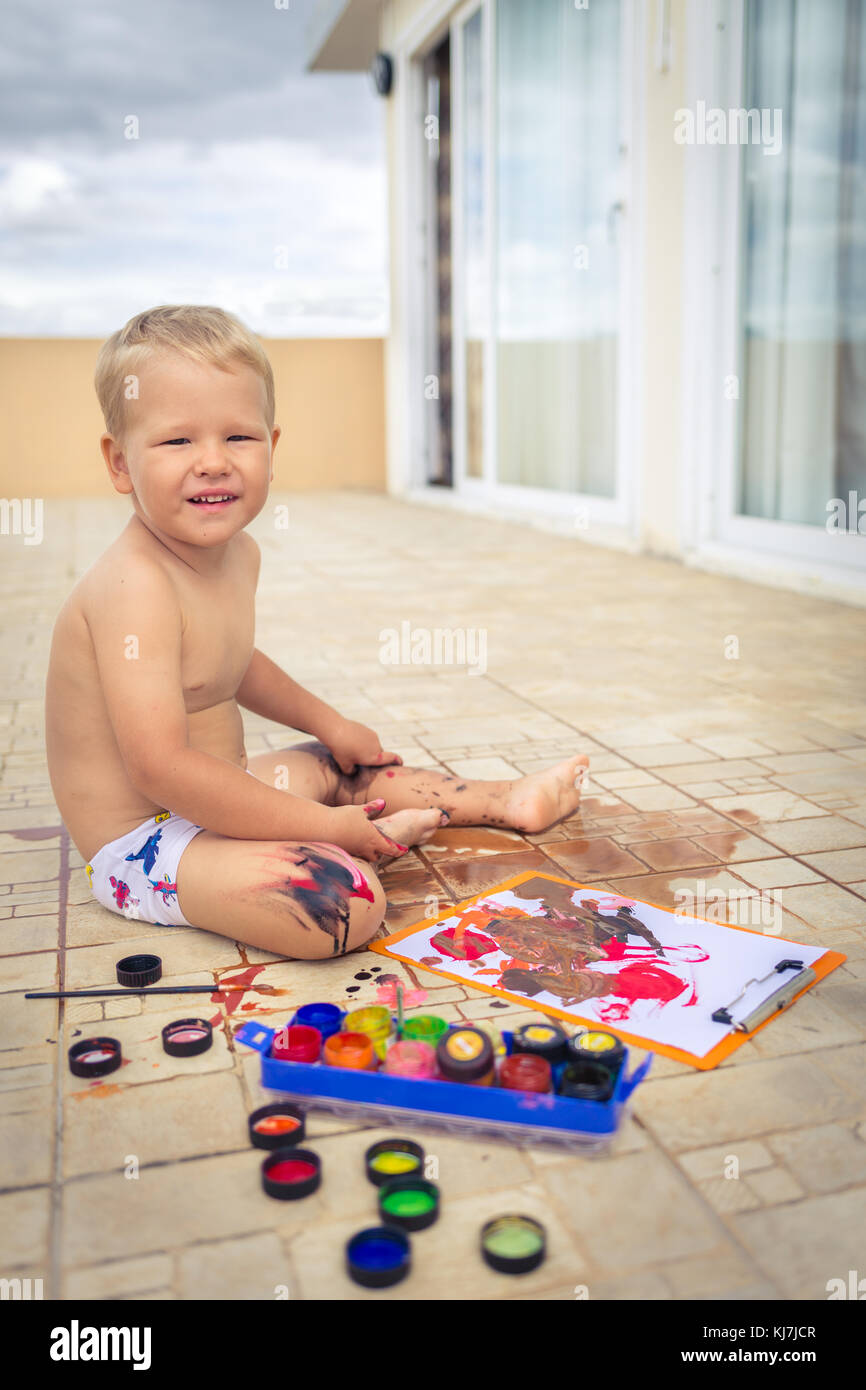 Boy practice to paint on paper sitting at terrace Stock Photo