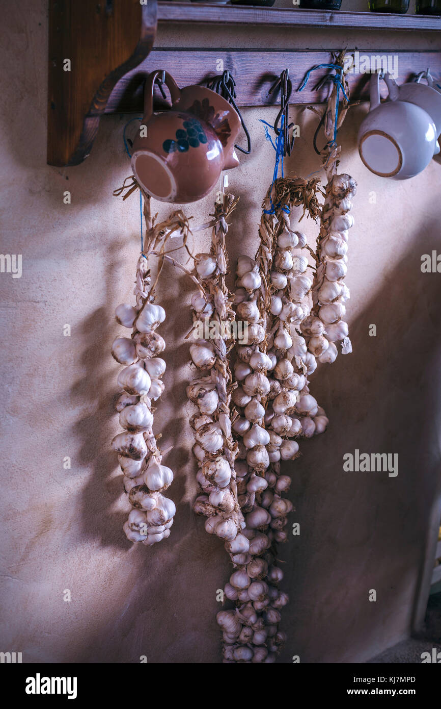 Garlic drying and hanging on the wall in rustic vintage kitchen Stock Photo