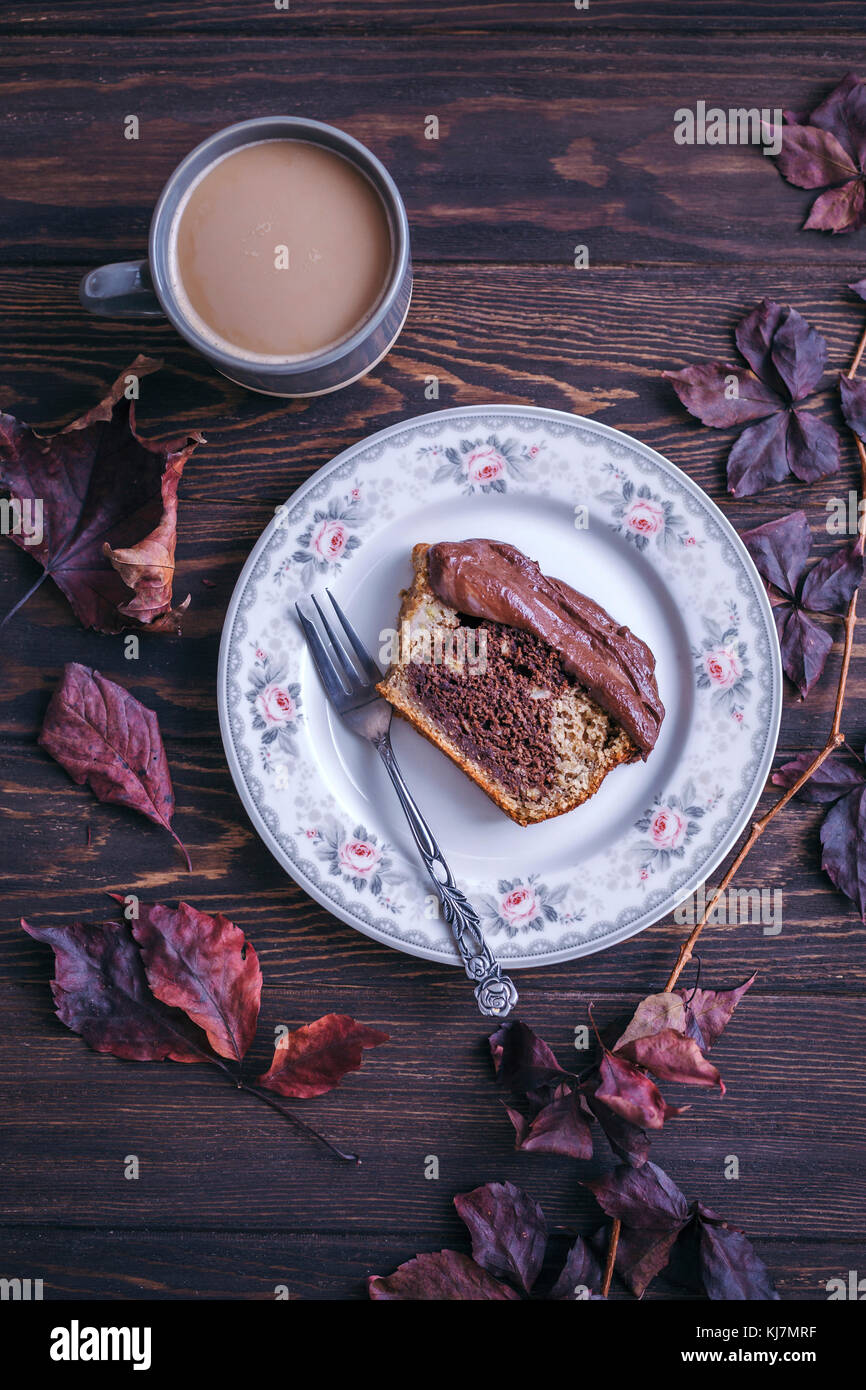 Slice of cake with chocolate ganache served on a dessert plate on dark rustic table Stock Photo