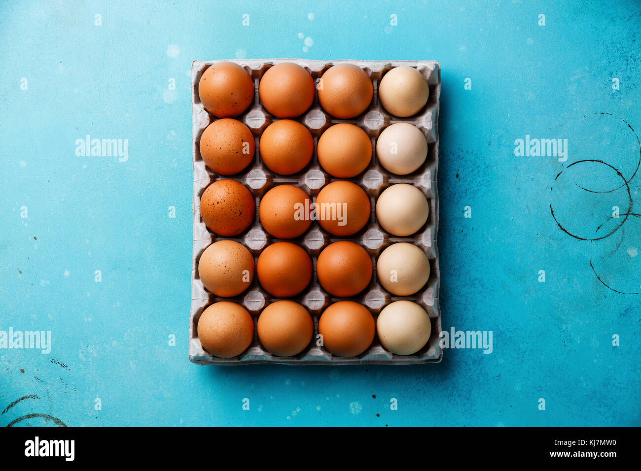 Fresh brown and speckled chicken Eggs in eco cardboard paper tray container on blue background Stock Photo